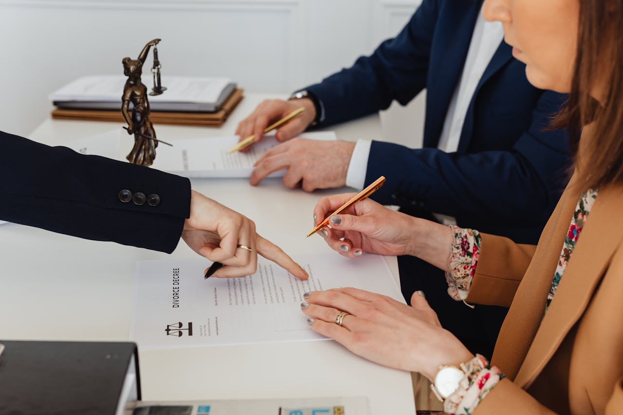 why-choose-us Hands signing a divorce decree, with a justice statue nearby, symbolizing legal proceedings.